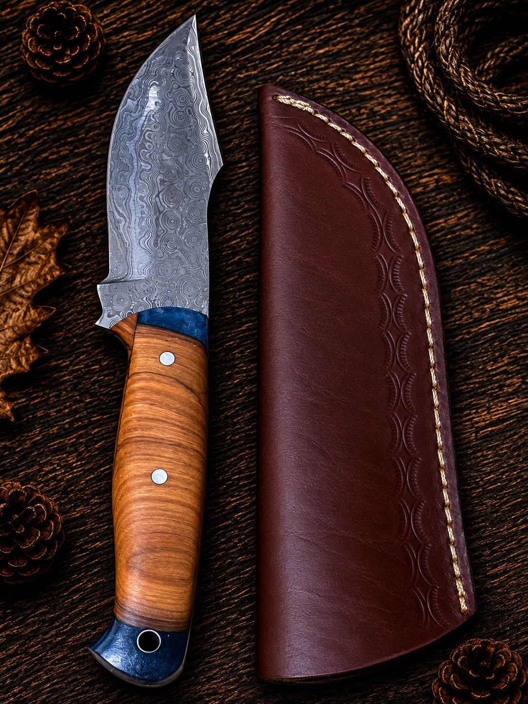 Damascus raindrop skinner knife with stacked leather handle and blue resin bolsters with embossed leather sheath