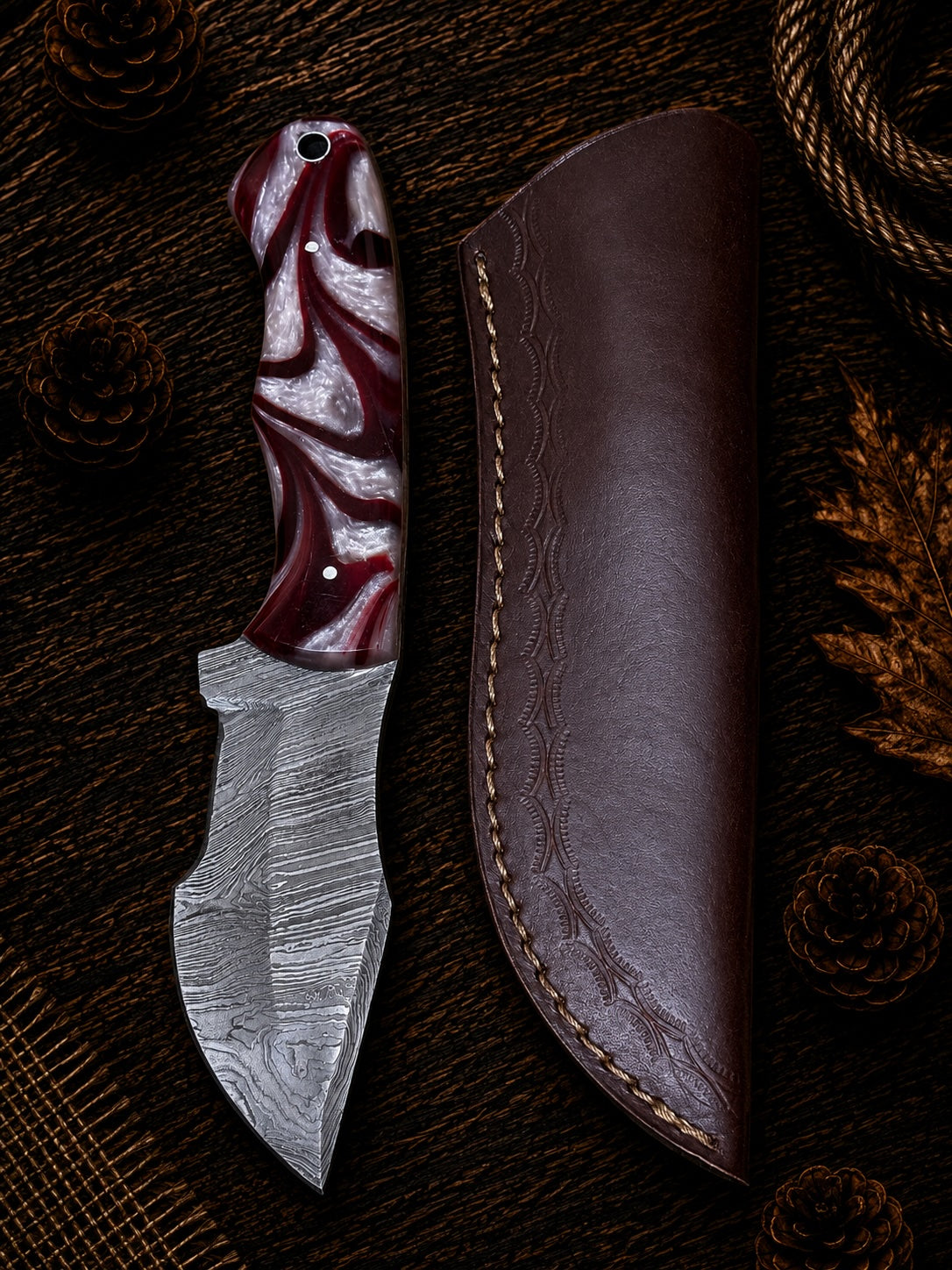 Compact Damascus skinner knife with crimson and pearl white swirl resin handle and embossed leather sheath